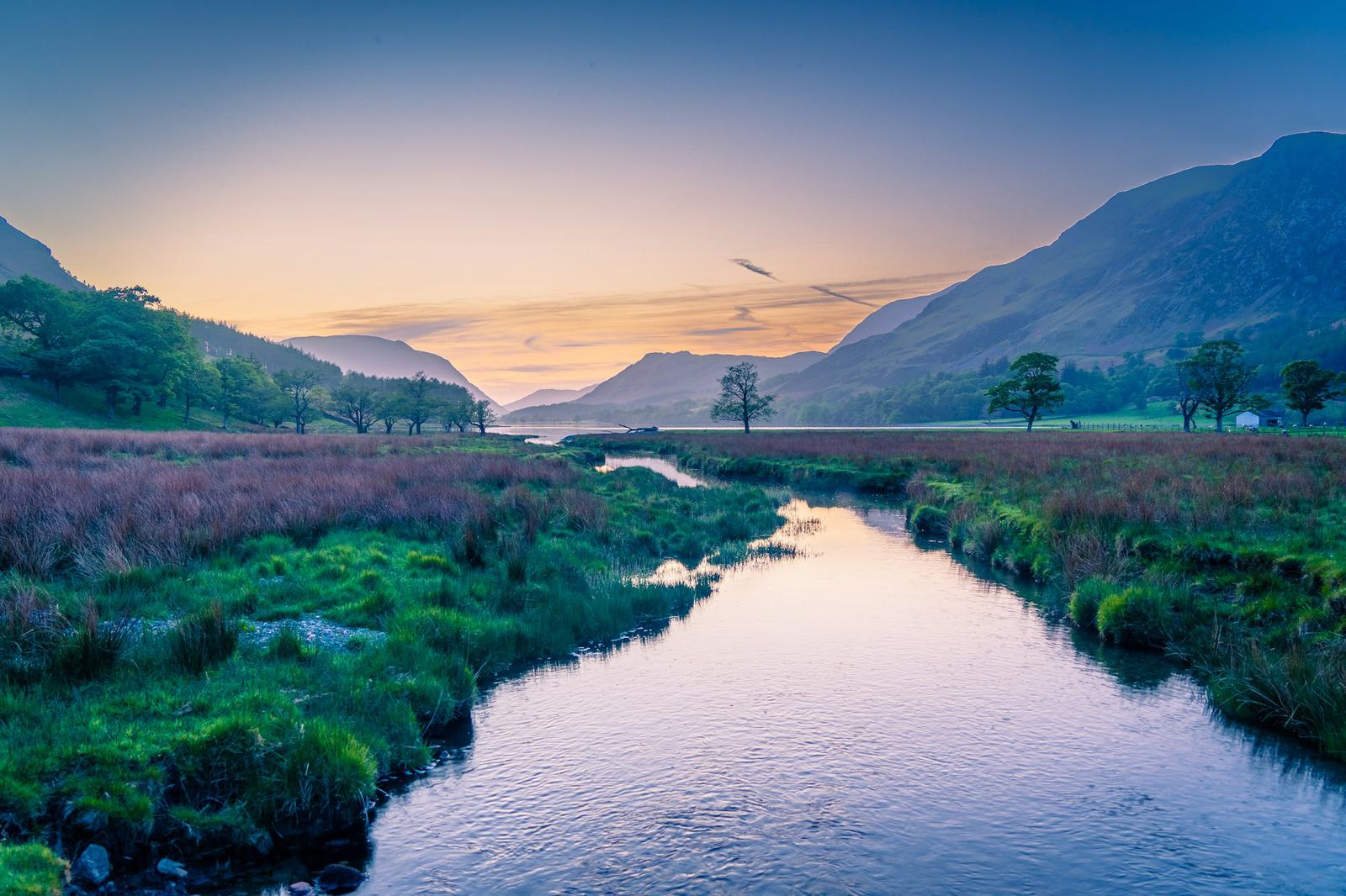 A river winding through green fields at dusk