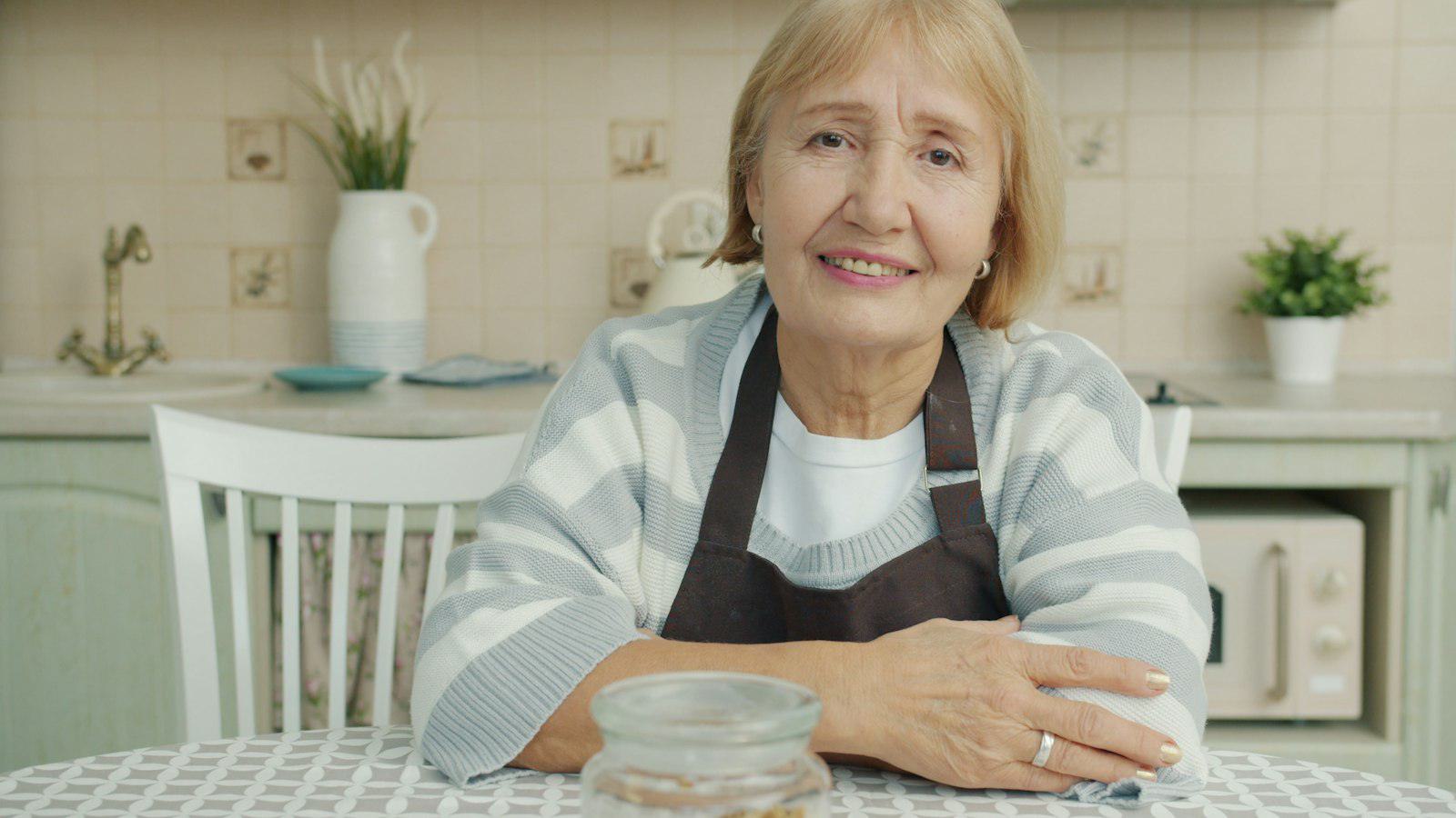 An older woman smiling at her kitchen table
